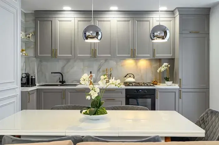 A kitchen with a table and chairs and a vase of flowers on the table.
