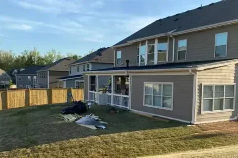 A large house with a screened in porch and a fence in the backyard.