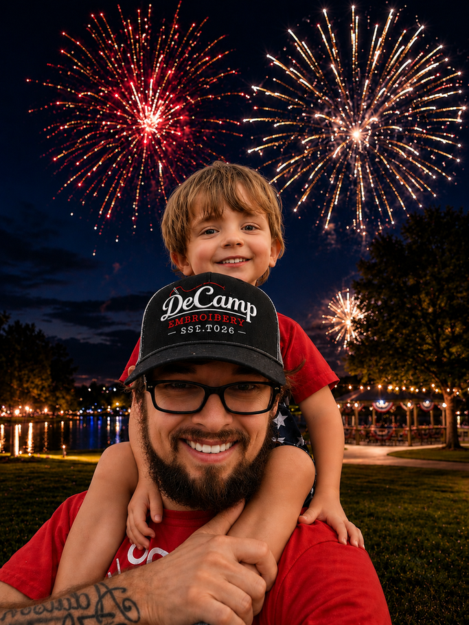 Smiling man giving a child a piggyback, with fireworks exploding over a waterfront at night.
