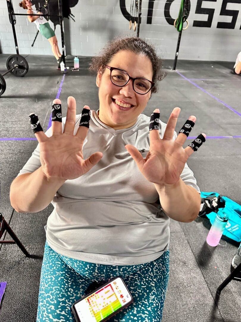 A woman wearing glasses is holding a cell phone in a gym.