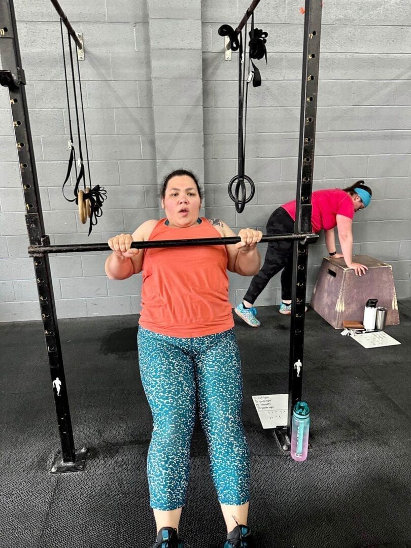 A woman is doing squats with a barbell in a gym.