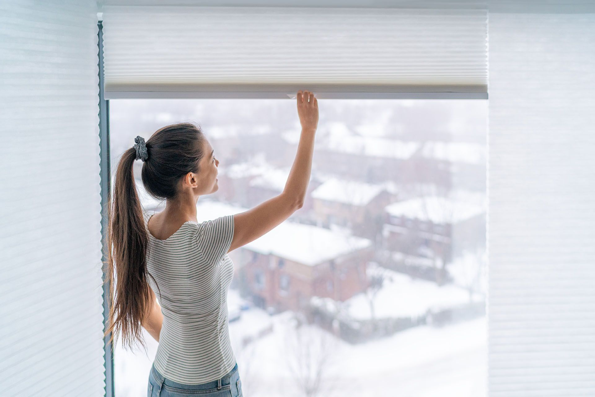 Woman opening windows shade blind during winter morning. Woman opening windows shade blind during winter morning.