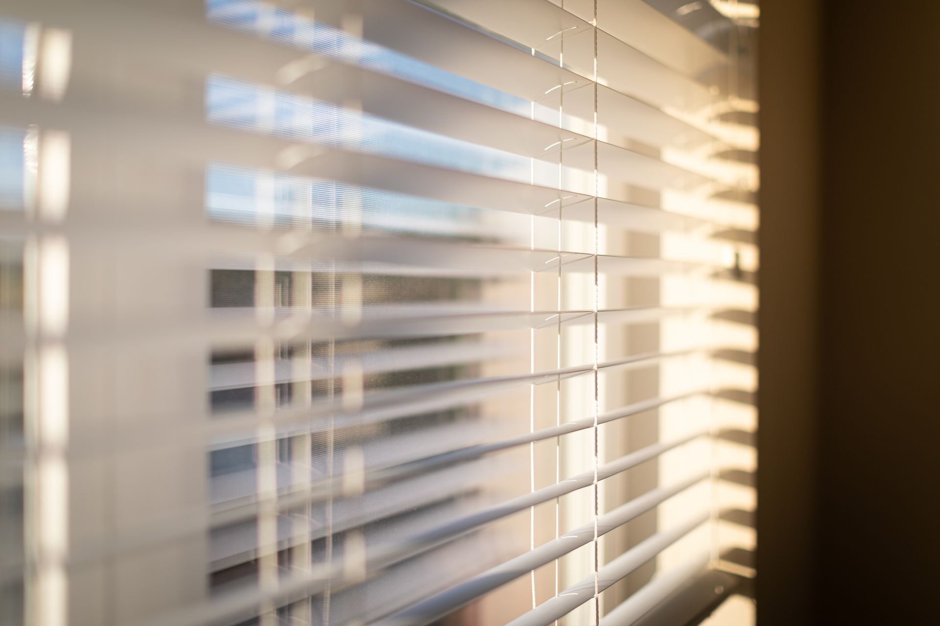 Sunlight filtering through white window blinds in a softly lit interior.