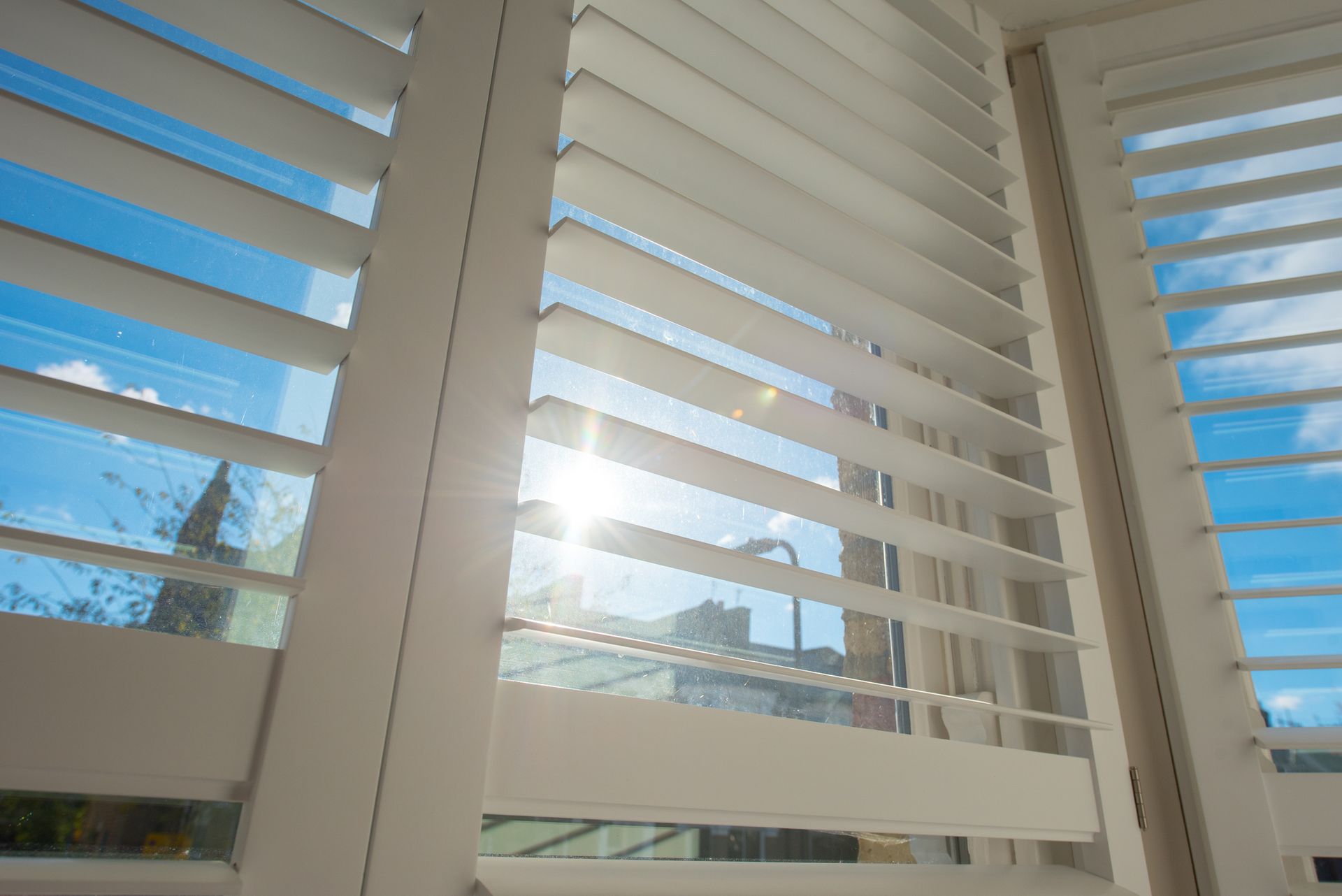 Interior view of open shutter window coverings in Dillon, MT with sunlight shining through, enhancing natural light control in the home. Interior view of open shutter window coverings in Dillon, MT with sunlight shining through, enhancing natural light control in the home.