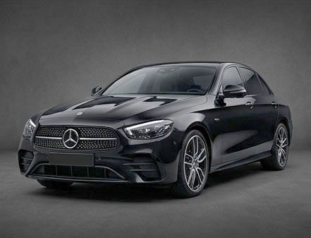 Berlina Mercedes-Benz nera su sfondo grigio in studio, vista frontale a tre quarti.