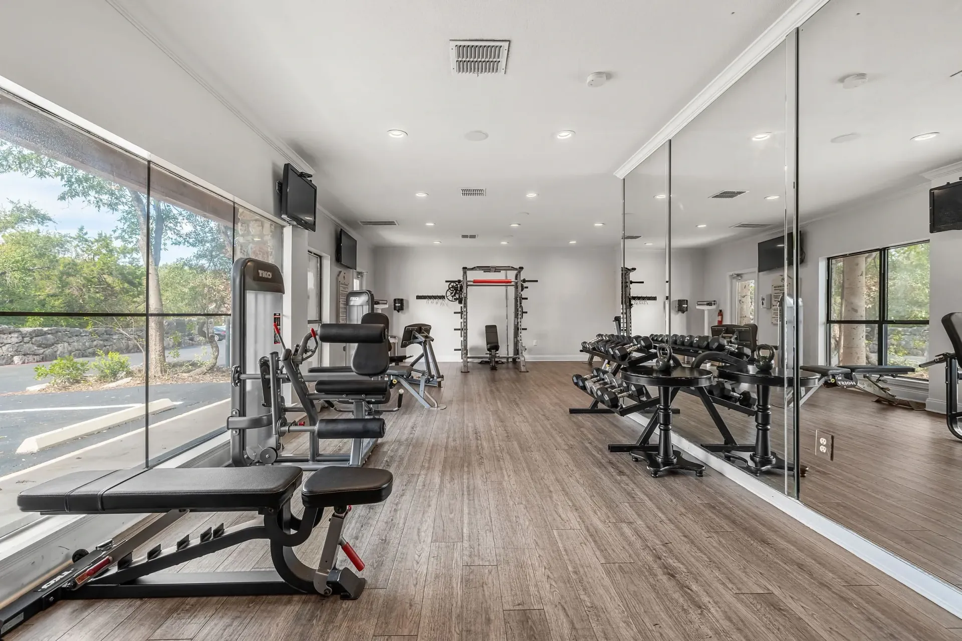 Fitness center with weight machines, free weights, and large mirrors.