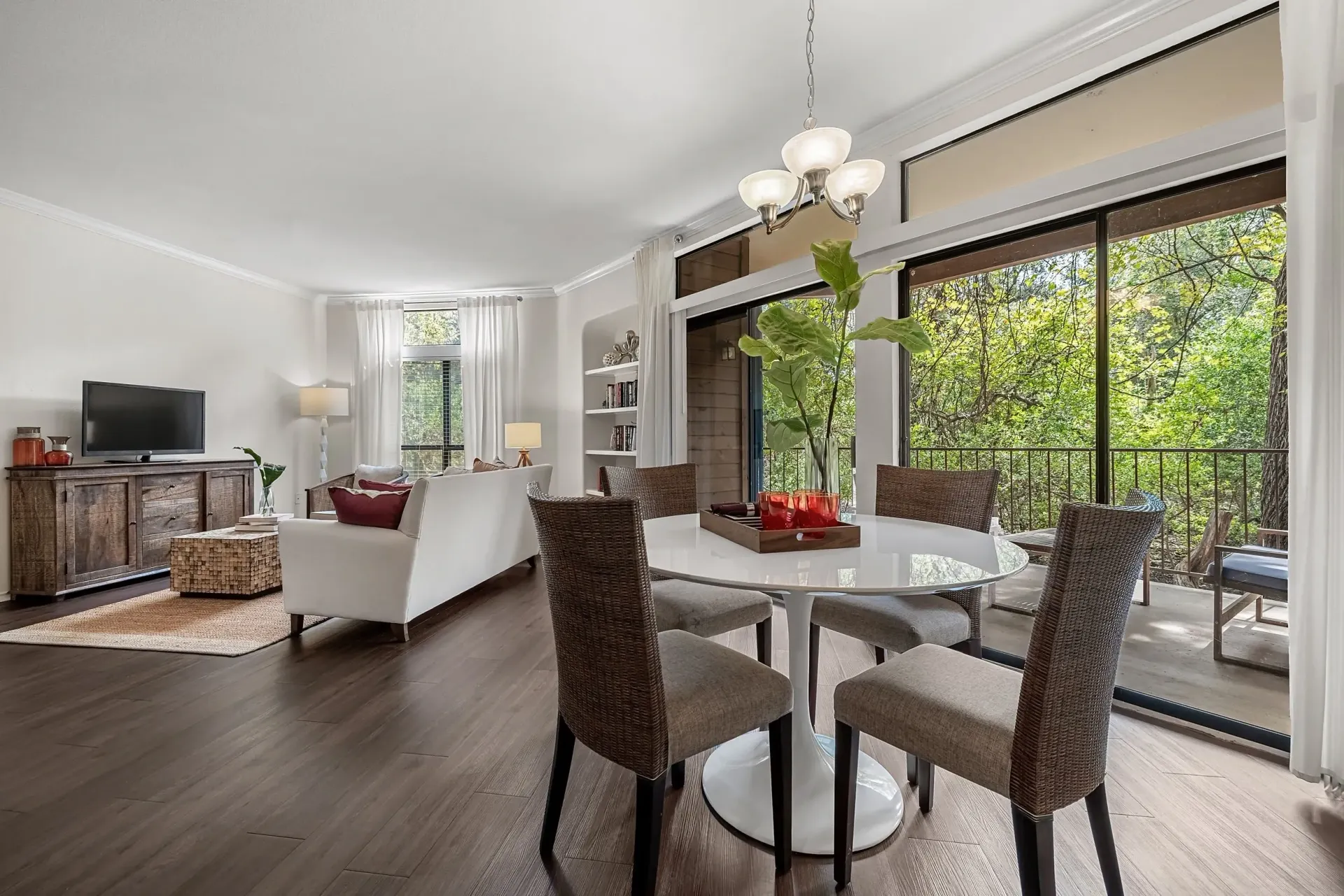 Dining area and living room with a balcony overlooking trees.