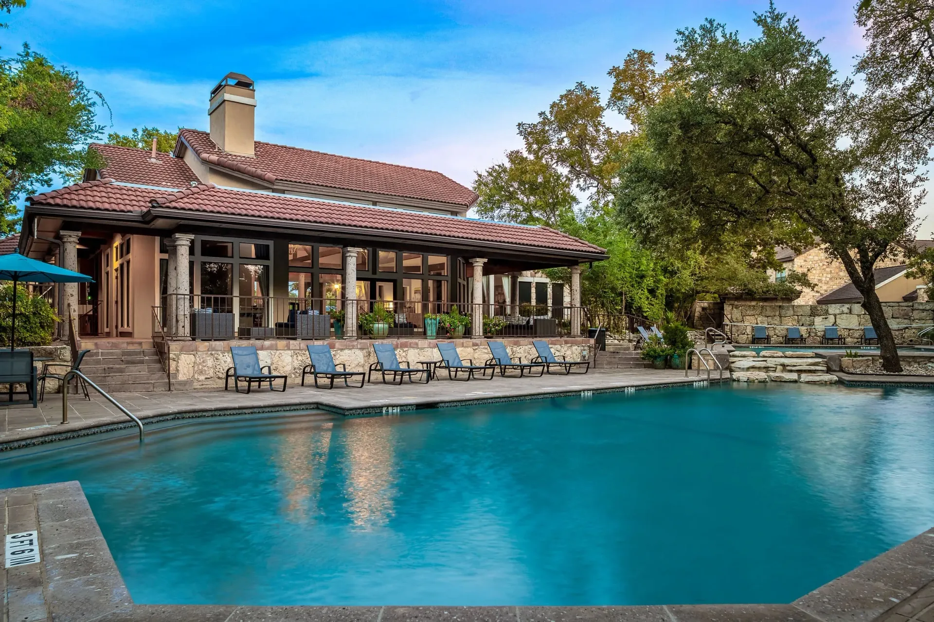 Resort-style swimming pool with lounge chairs and a clubhouse in the background.