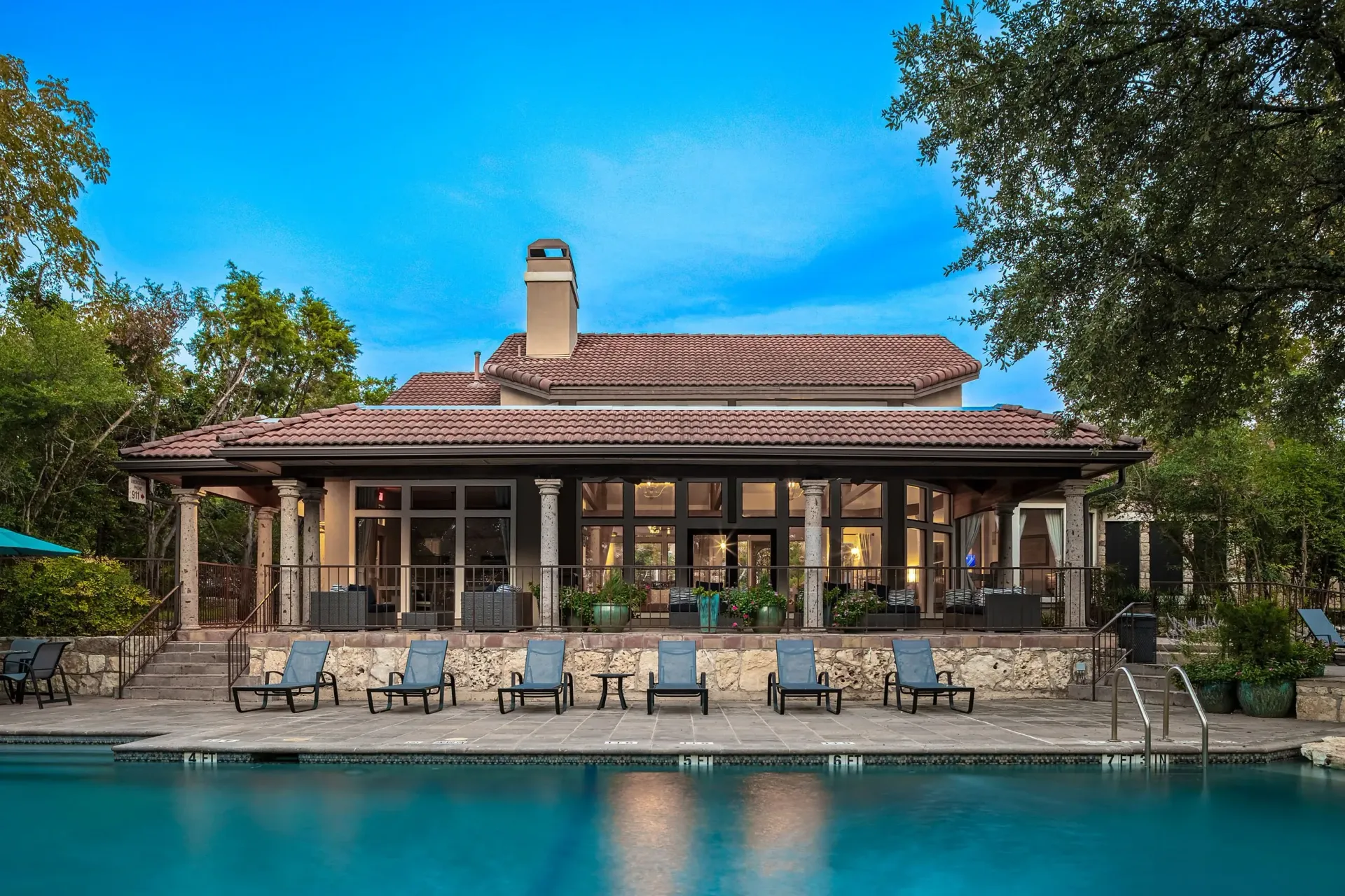 Resort-style swimming pool and clubhouse with lounge chairs.