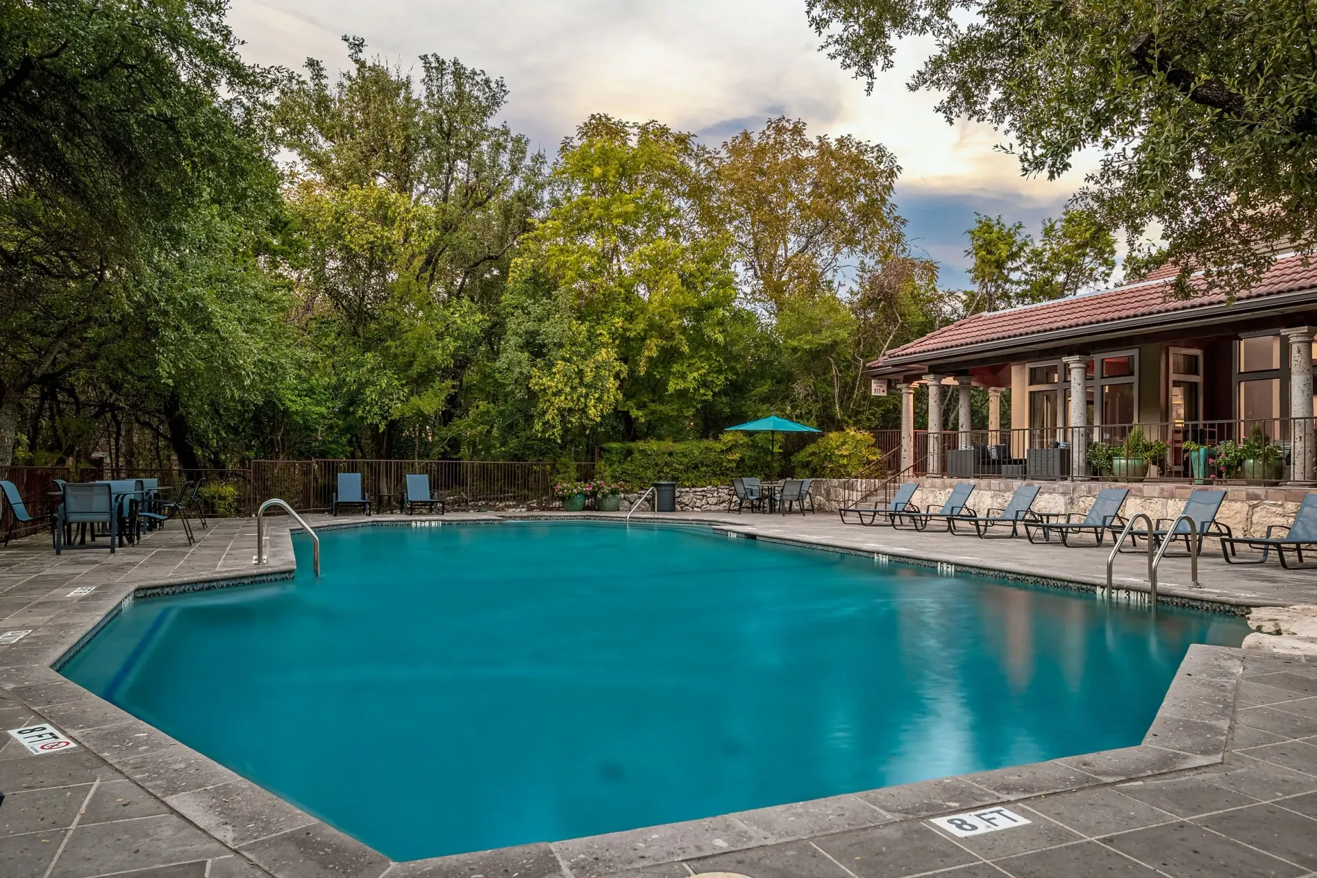 Resort-style swimming pool with lounge chairs and umbrellas.