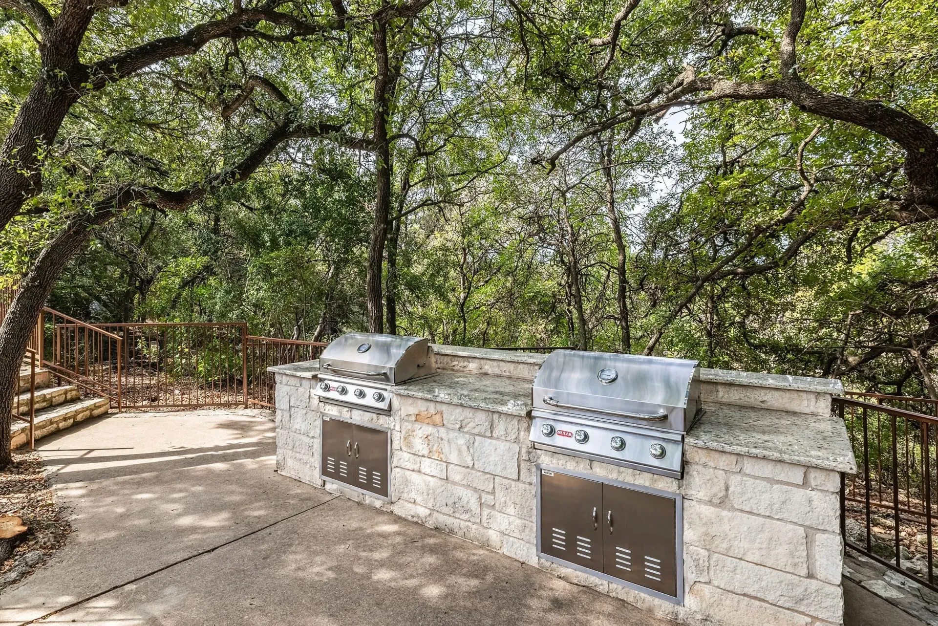 Outdoor kitchen with two stainless steel grills built into a stone counter.