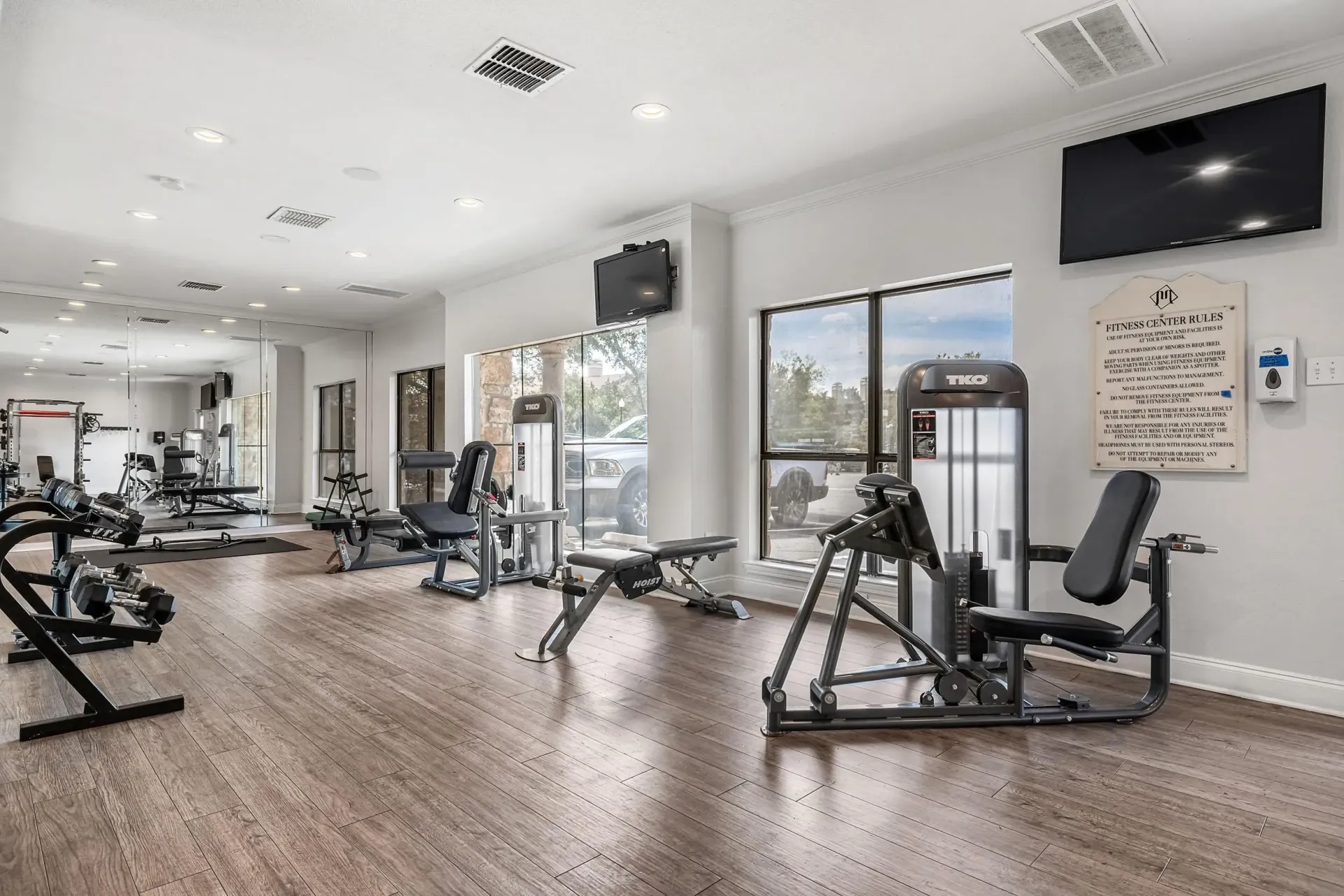 Interior of a well-equipped fitness center with weight machines, free weights, and TVs.