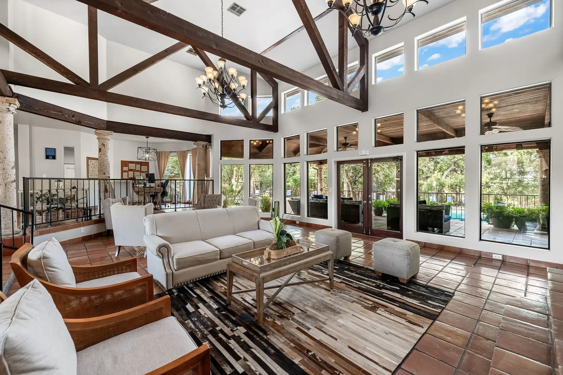 Elegant lounge area with a sectional sofa, coffee table, and chairs, overlooking a pool.