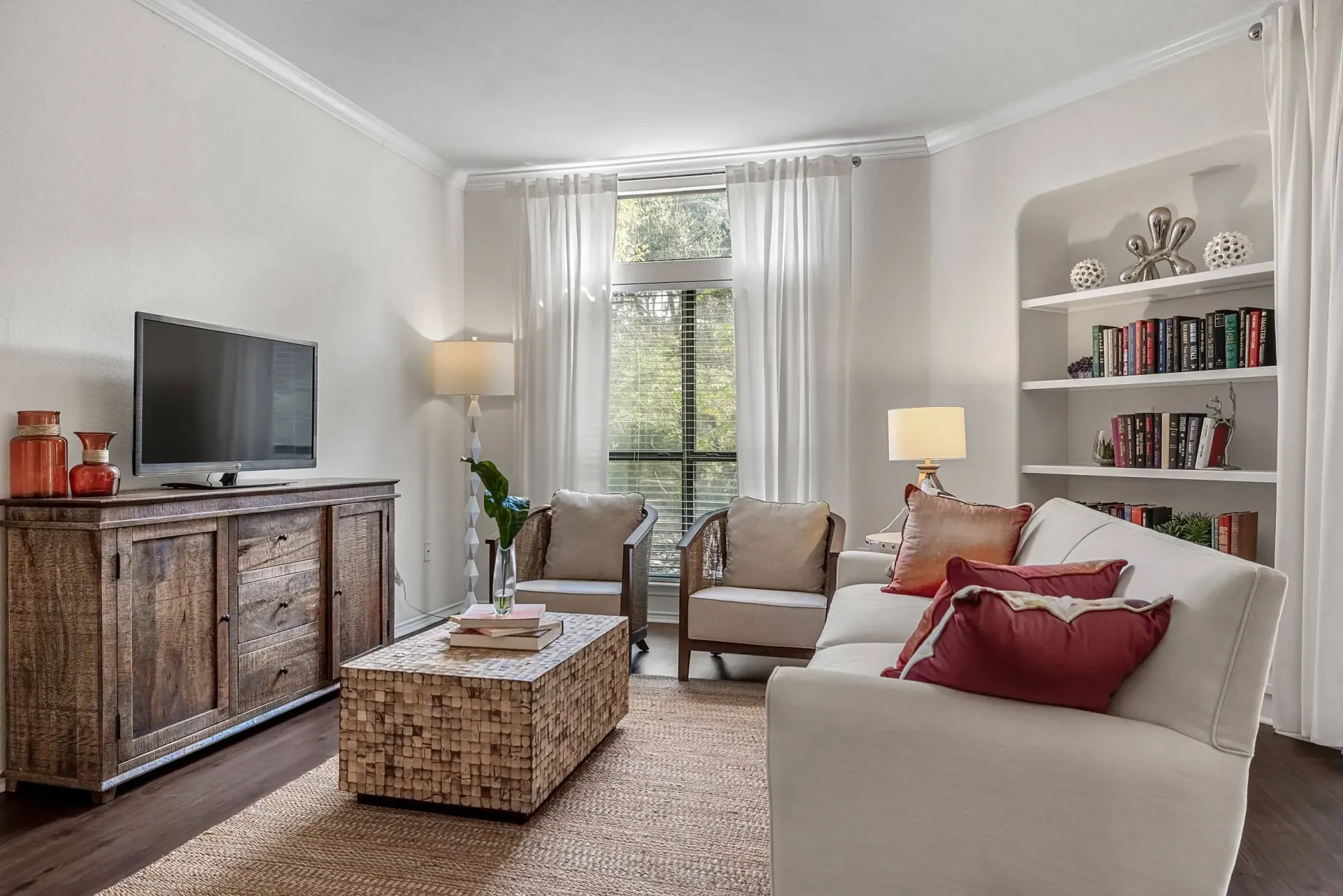 Living room with a sofa, armchairs, coffee table, TV, and bookshelves.