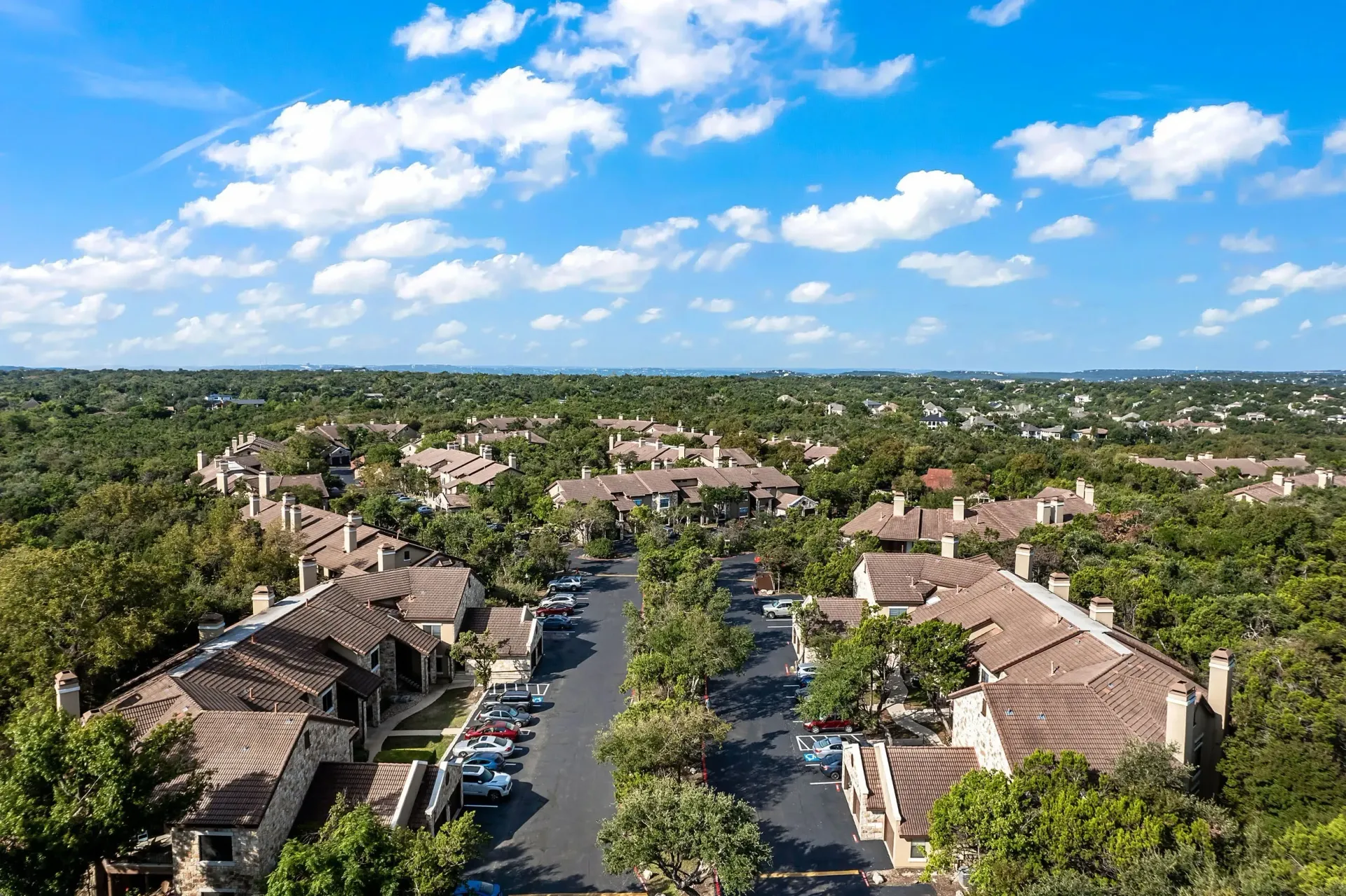 Aerial view of apartment buildings surrounded by lush greenery and trees.