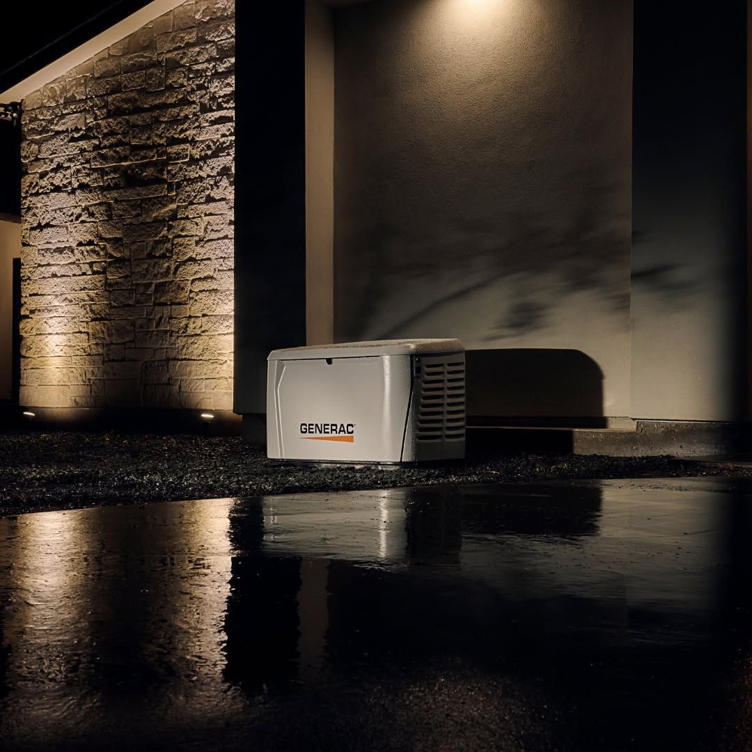 White HVAC unit outside a building at night, with warm wall lights reflecting on wet pavement