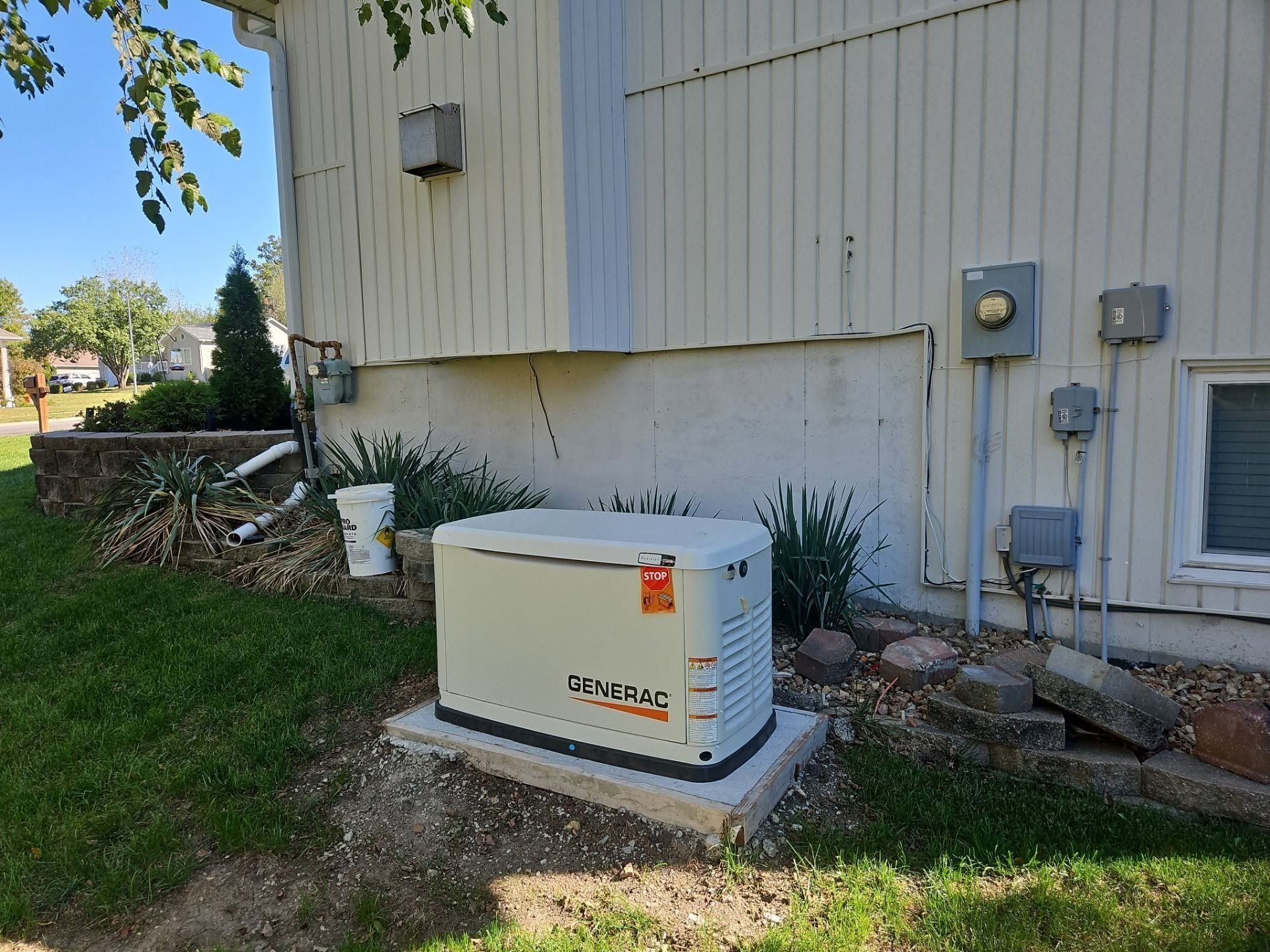 Outdoor generator beside beige house with utility meters and grass yard