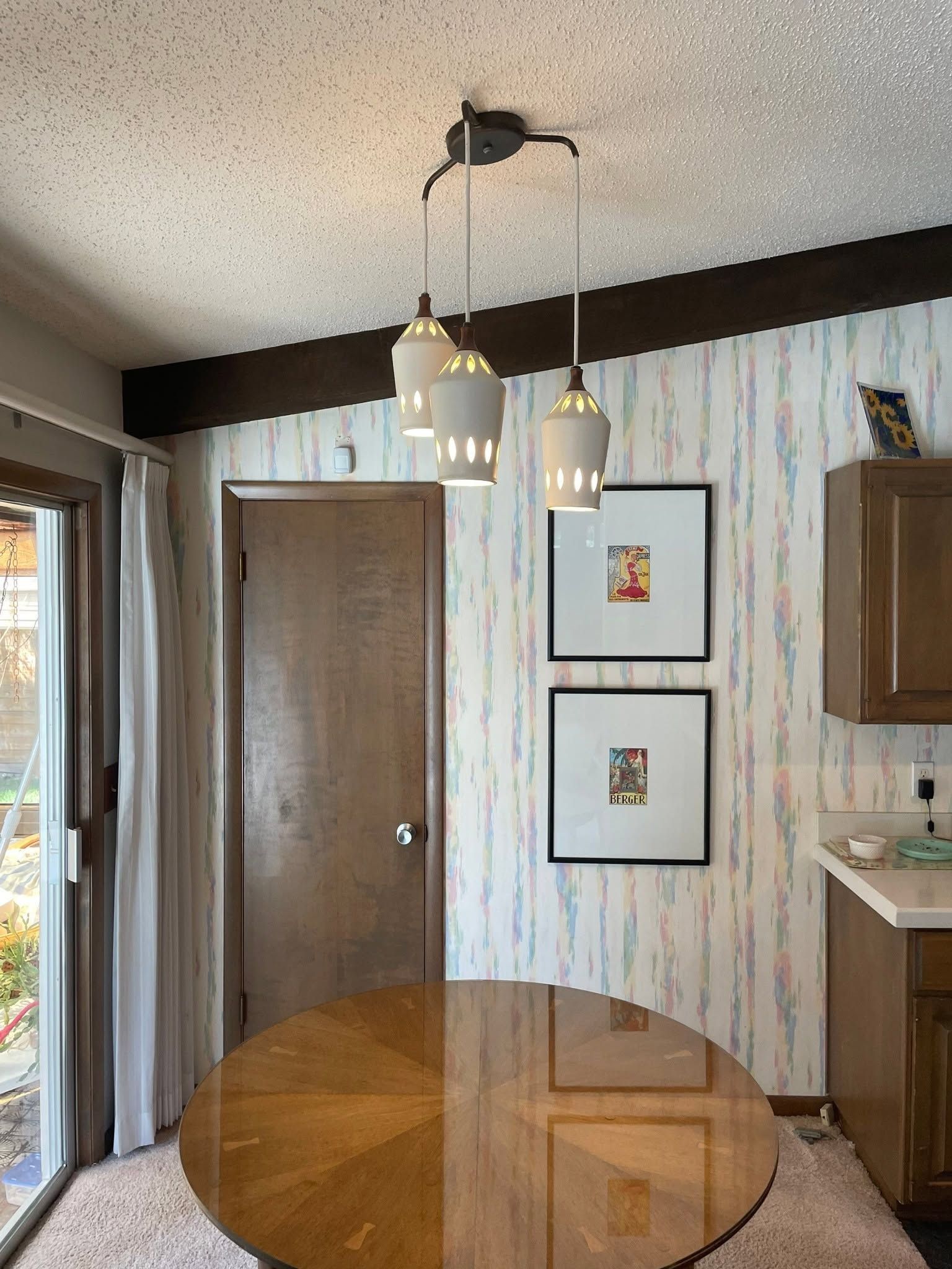 Small dining area with hanging light, wood door, framed art, and table edge visible