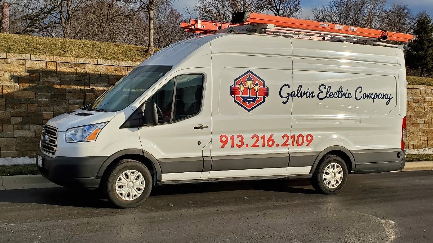 White service van with ladder rack and “Galaxy Electric Company” logo parked by a stone wall