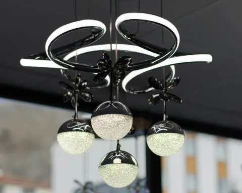 Black modern chandelier with five frosted glass globe lights on a ceiling in a showroom