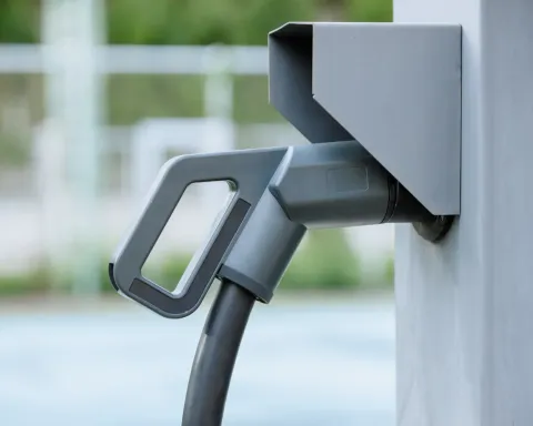 Close-up of an electric vehicle charging plug connected to a gray charging station