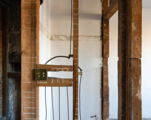 Exposed wall studs and electrical wiring in a room under renovation, with a white radiator below.