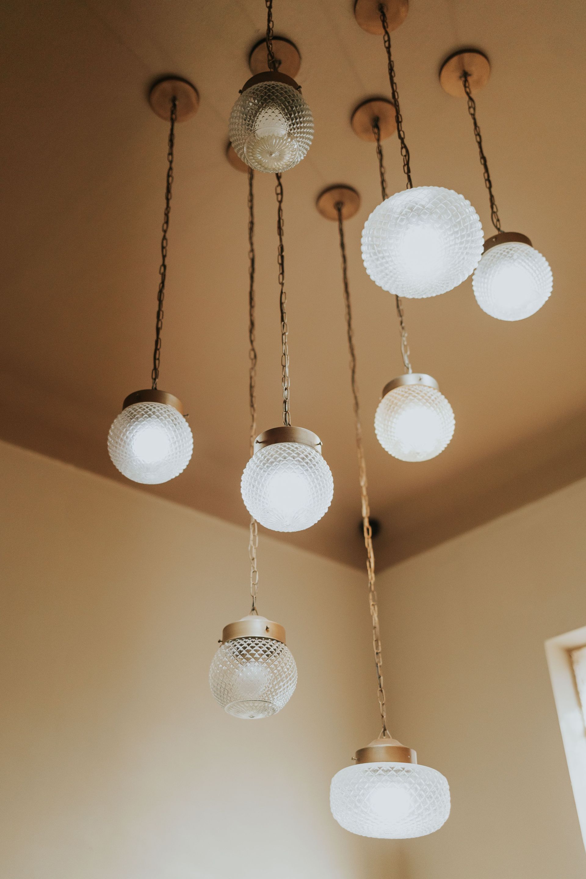 Cluster of hanging pendant lights with white glass globes on a tan ceiling