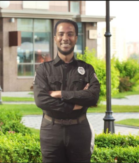 A man in a black uniform is standing with his arms crossed