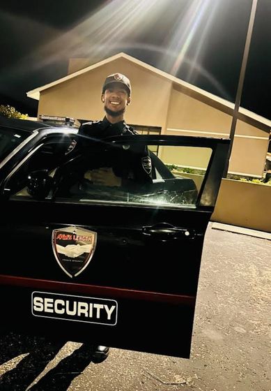 A man is standing next to a security vehicle at night.