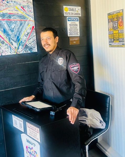 A man in a police uniform is standing in front of a desk.