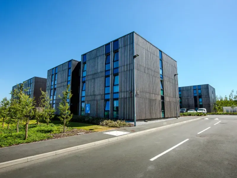 A large building with a lot of windows is sitting next to a road.