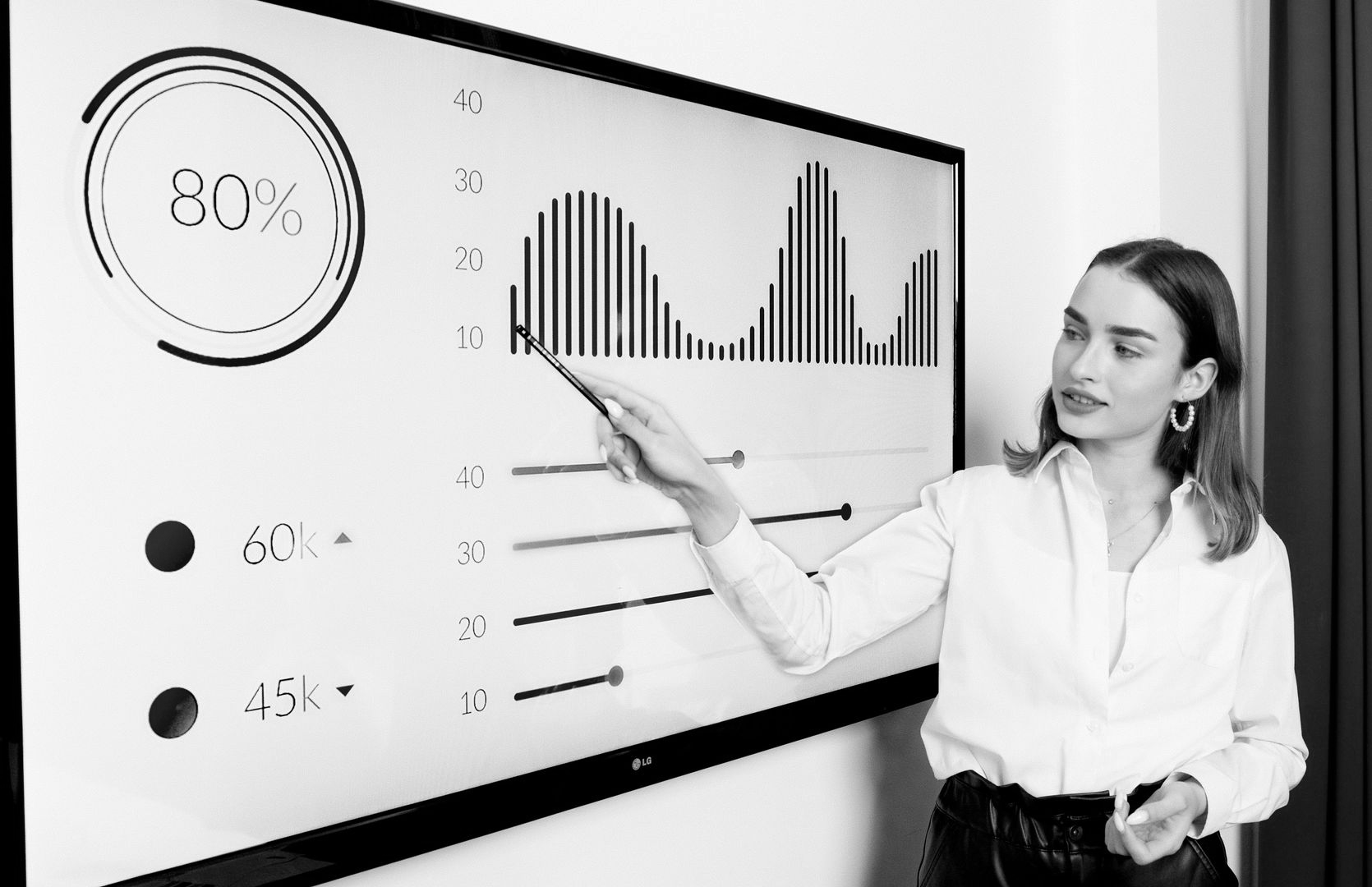 Two women writing on whiteboard in office, one smiling.