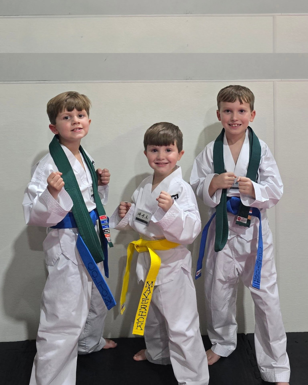 Three cousins smiling after earning new belts at Tennessee Taekwondo in Mt. Juliet, TN