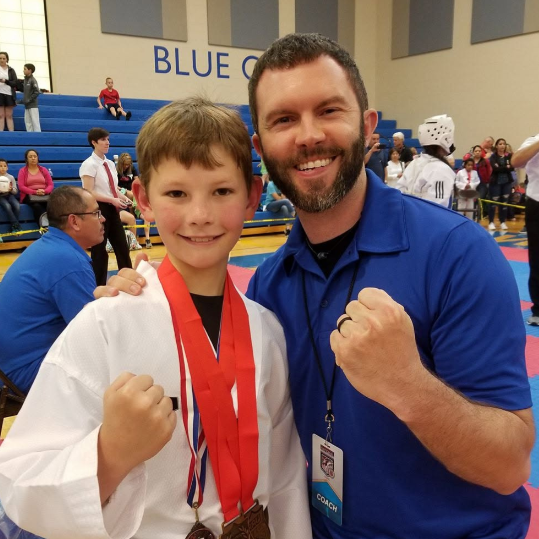Young student celebrating a tournament medal with Master Dustin Sands