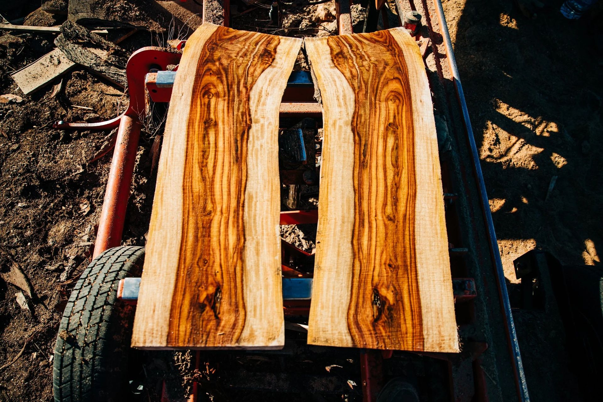 Two wood planks with unique grain patterns, sitting on a red hand truck.