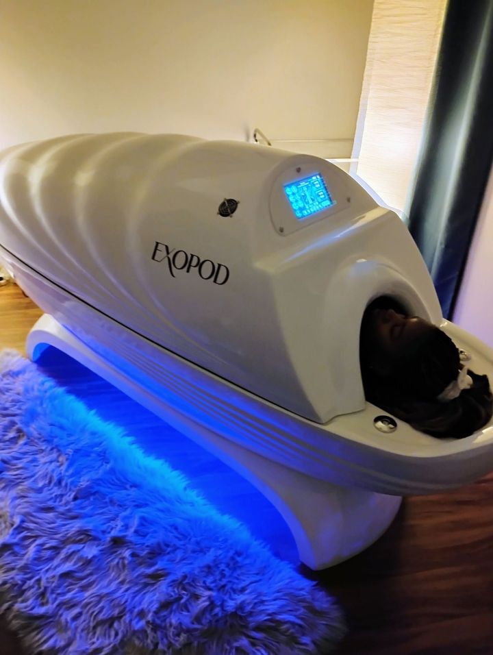 White pet pod on blue-lit furry rug, with a cat’s head peeking out through the front opening.