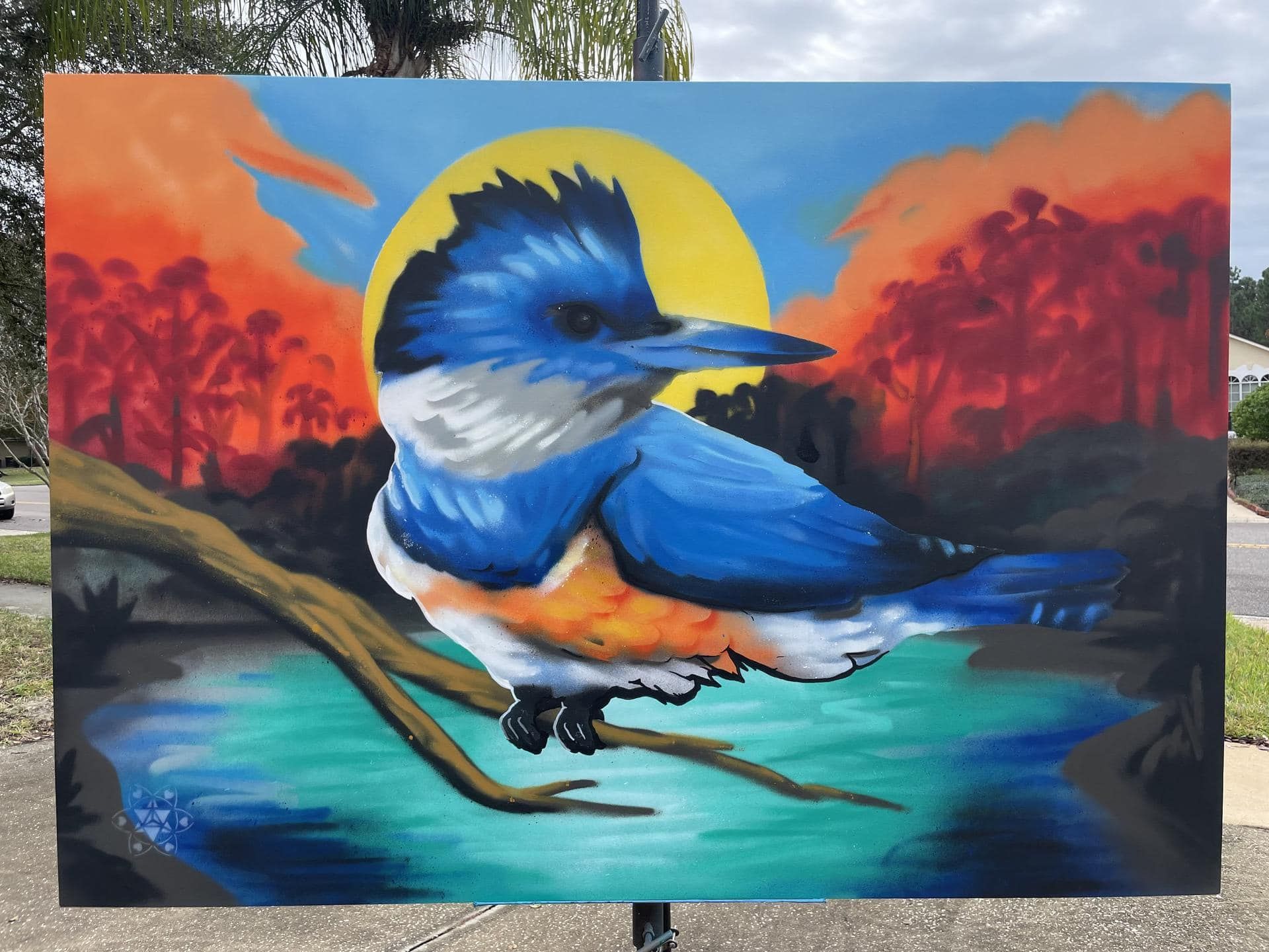 Spray painted art created live as a painting performance at the St. Johns River Keepers Annual Oyster Roast event in Jacksonville, Florida. The painting features a King Fisher bird and a Florida native landscape at dusk.