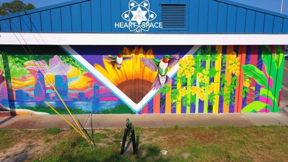 Spray Painted mural located in Riverside Jacksonville, Florida. Features bright vibrant colors, and natural subject matter like leaves, hummingbird, bee, and sunflower.