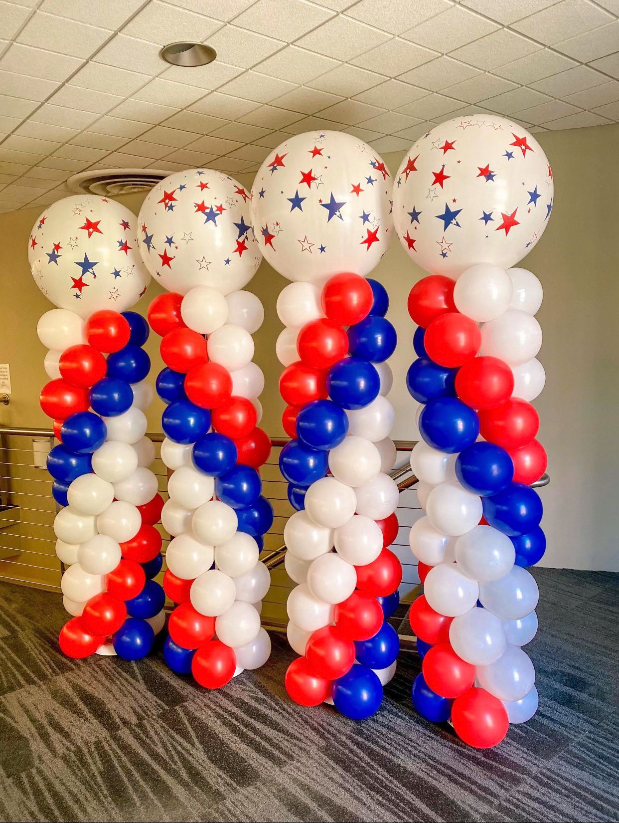 A row of red , white , and blue balloons stacked on top of each other in a room.