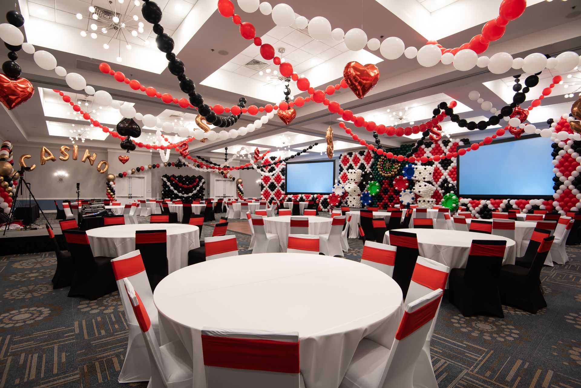 A large room with tables and chairs and balloons hanging from the ceiling