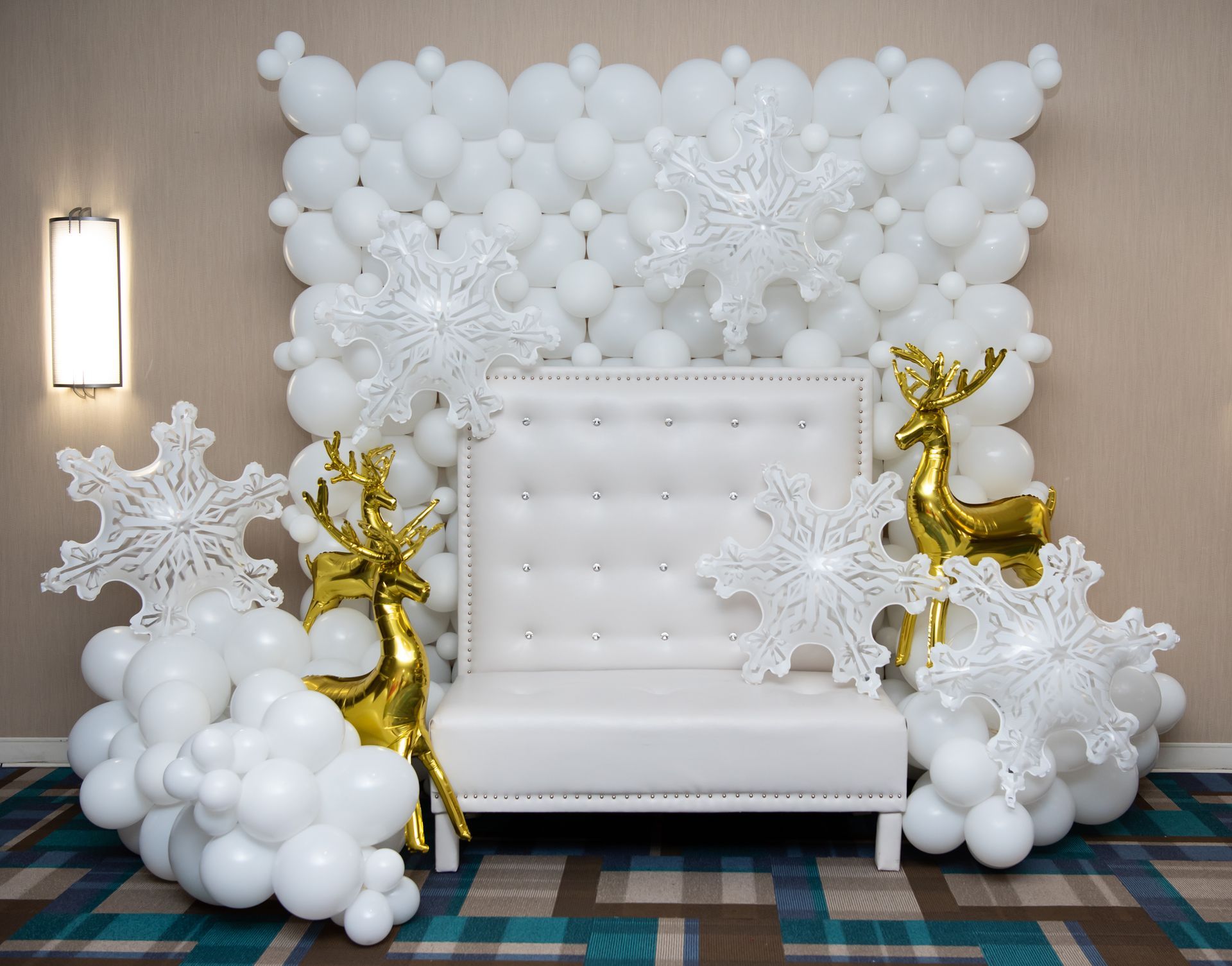 A white couch is surrounded by white balloons and snowflakes.