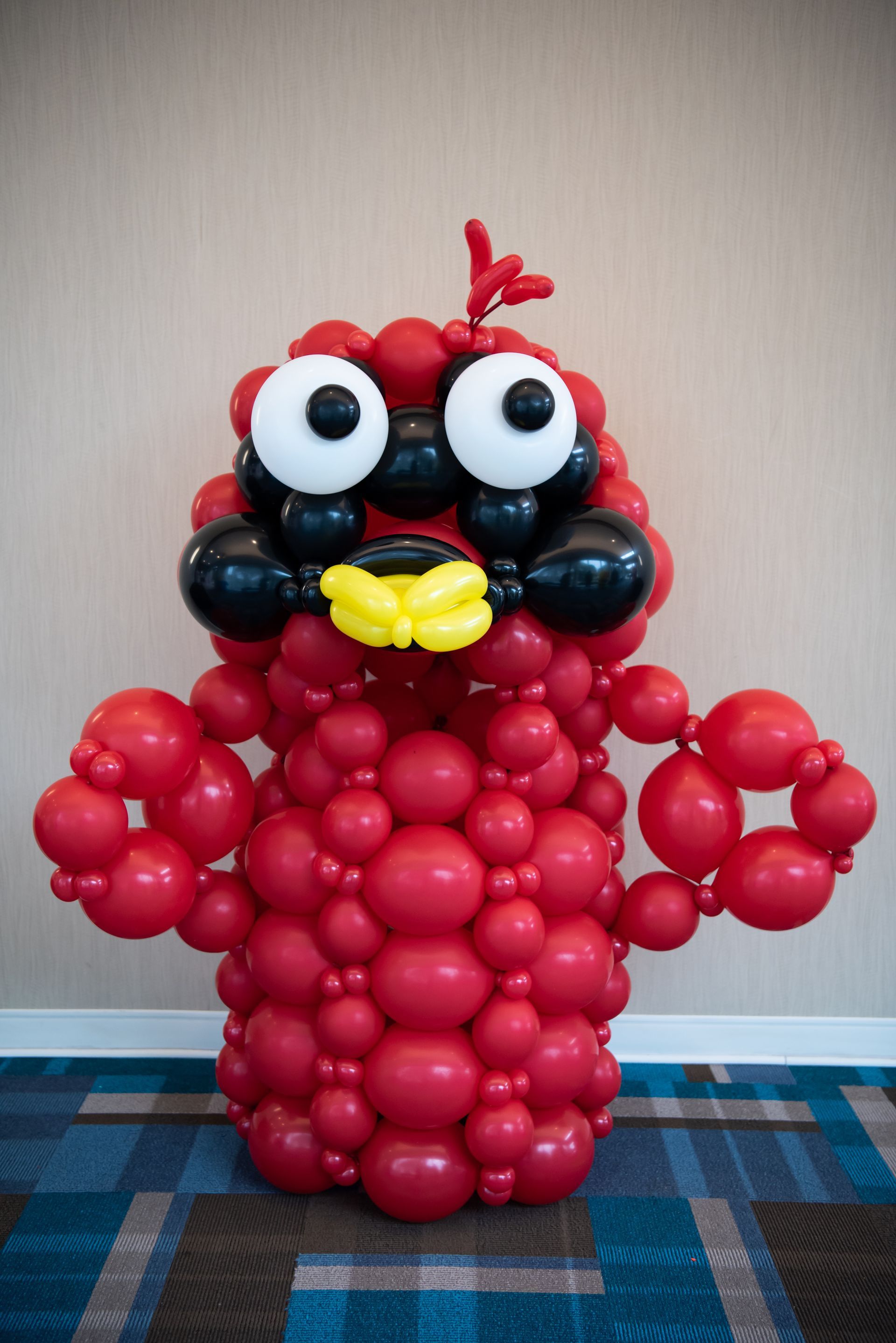 A balloon sculpture of an angry bird made of red and black balloons.