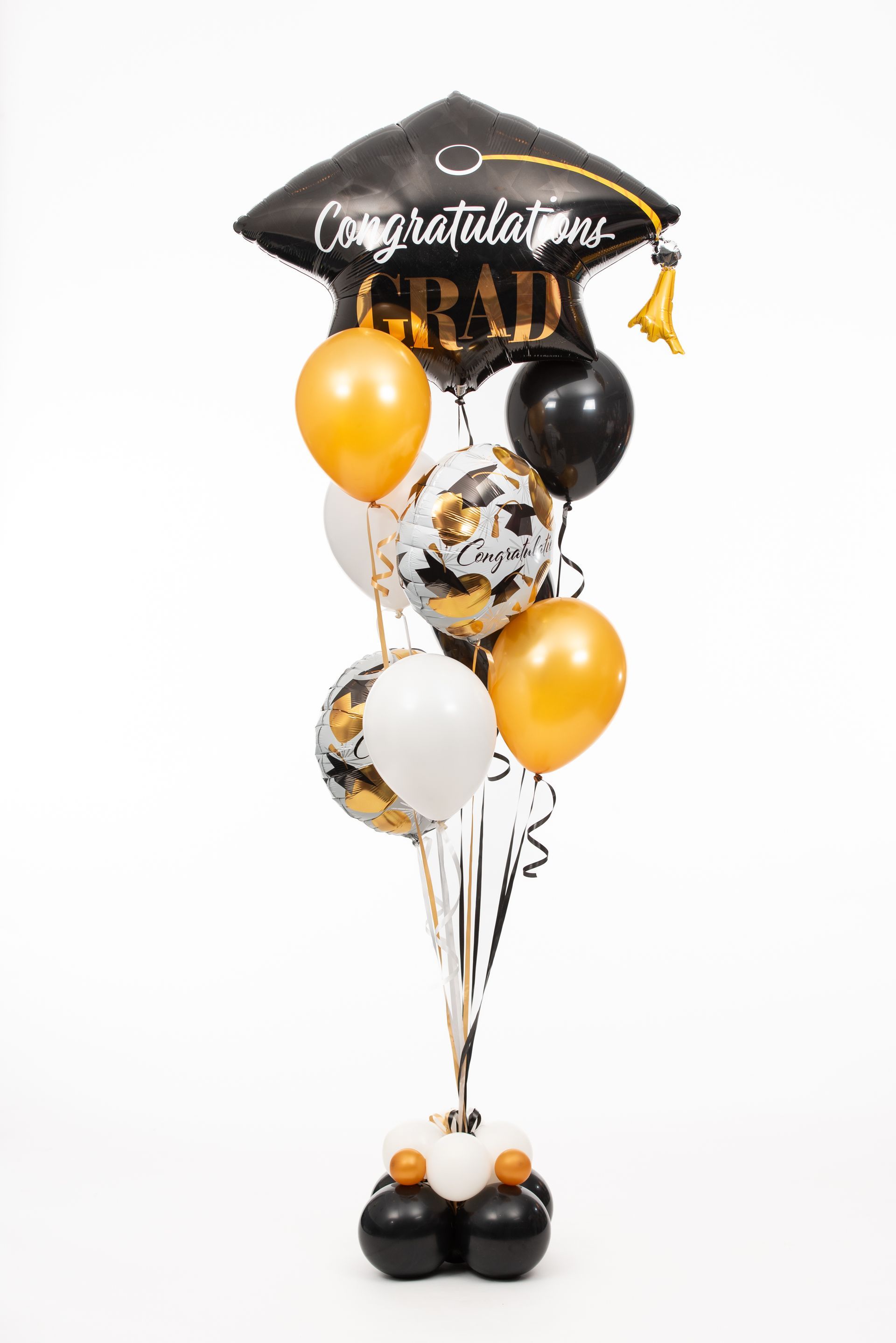 A bunch of balloons with a graduation cap on top of them.