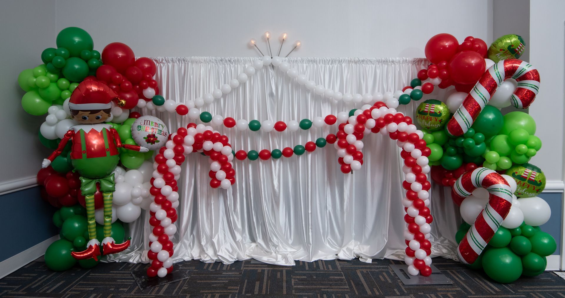 A wall decorated with balloons and candy canes for a christmas party.