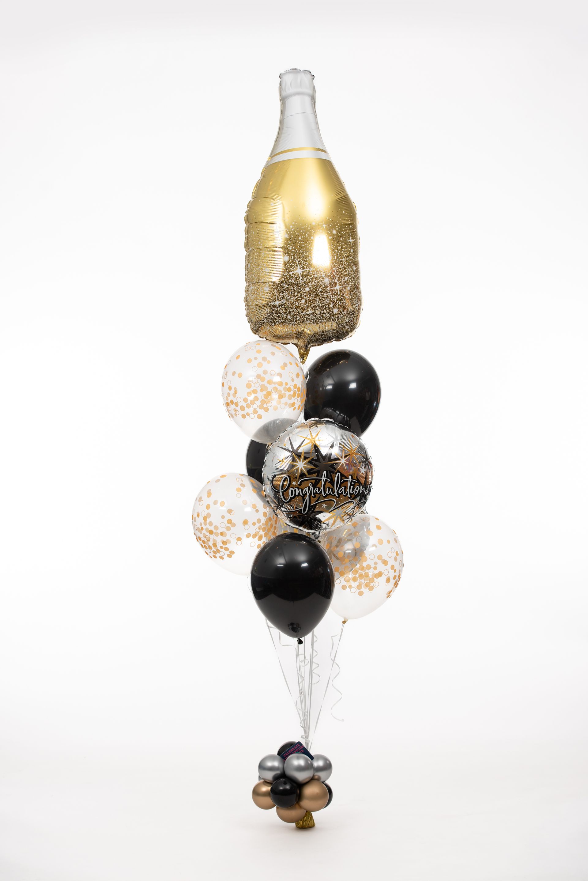 A bottle of champagne is surrounded by black and gold balloons.