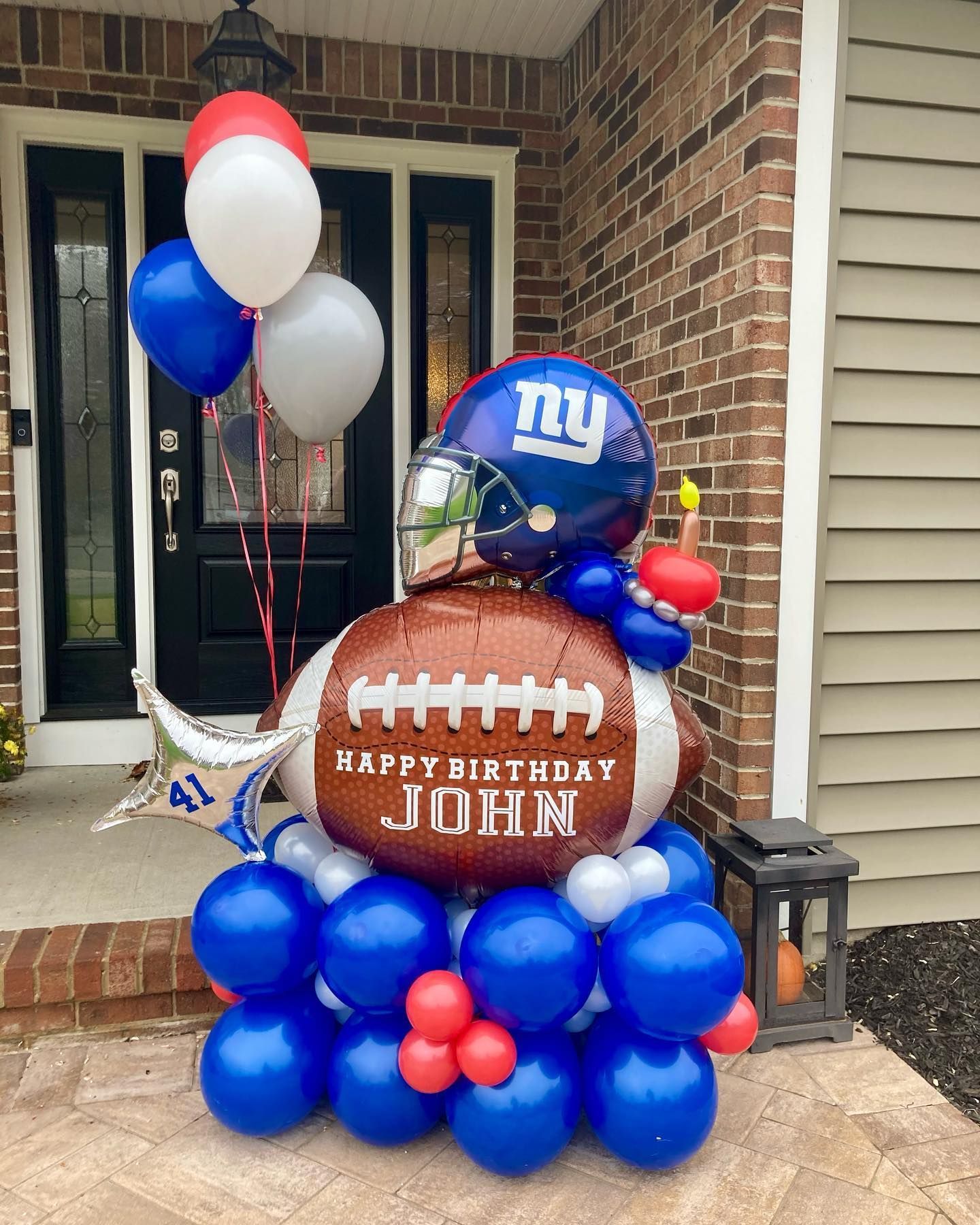 A bunch of balloons are stacked on top of each other in front of a brick building.