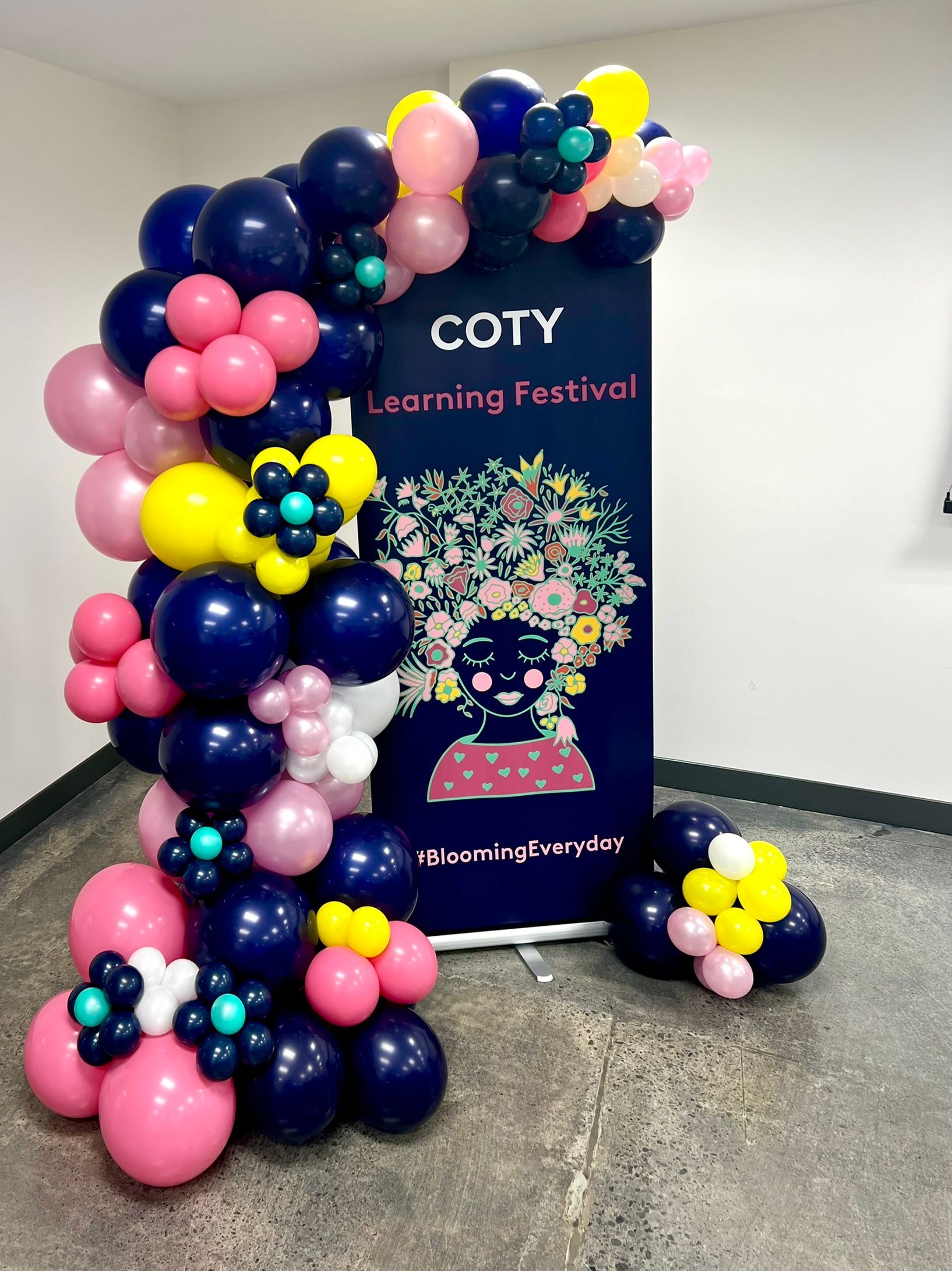 A bunch of balloons are sitting next to a sign in a room.