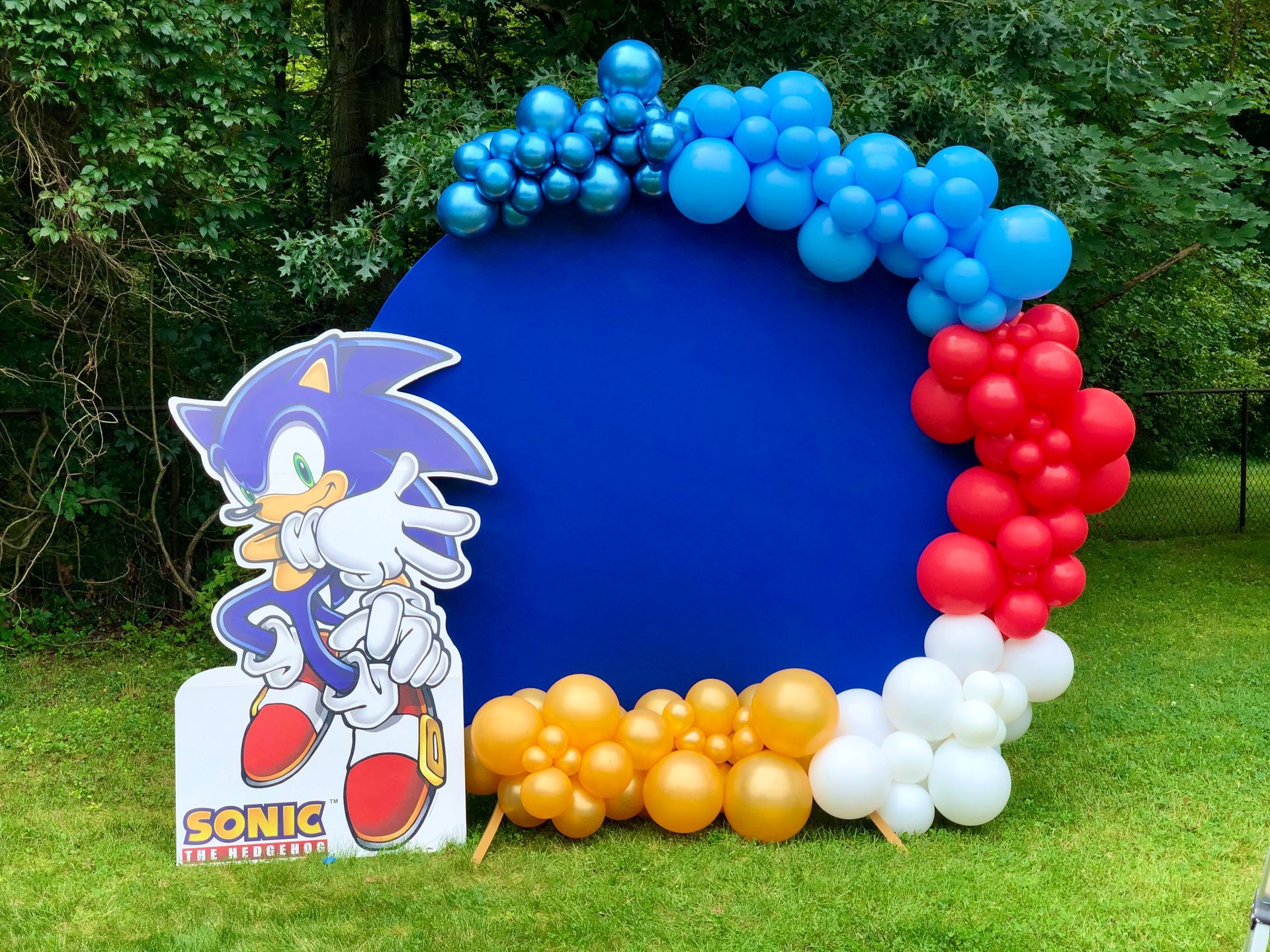A sonic the hedgehog sign is surrounded by balloons.