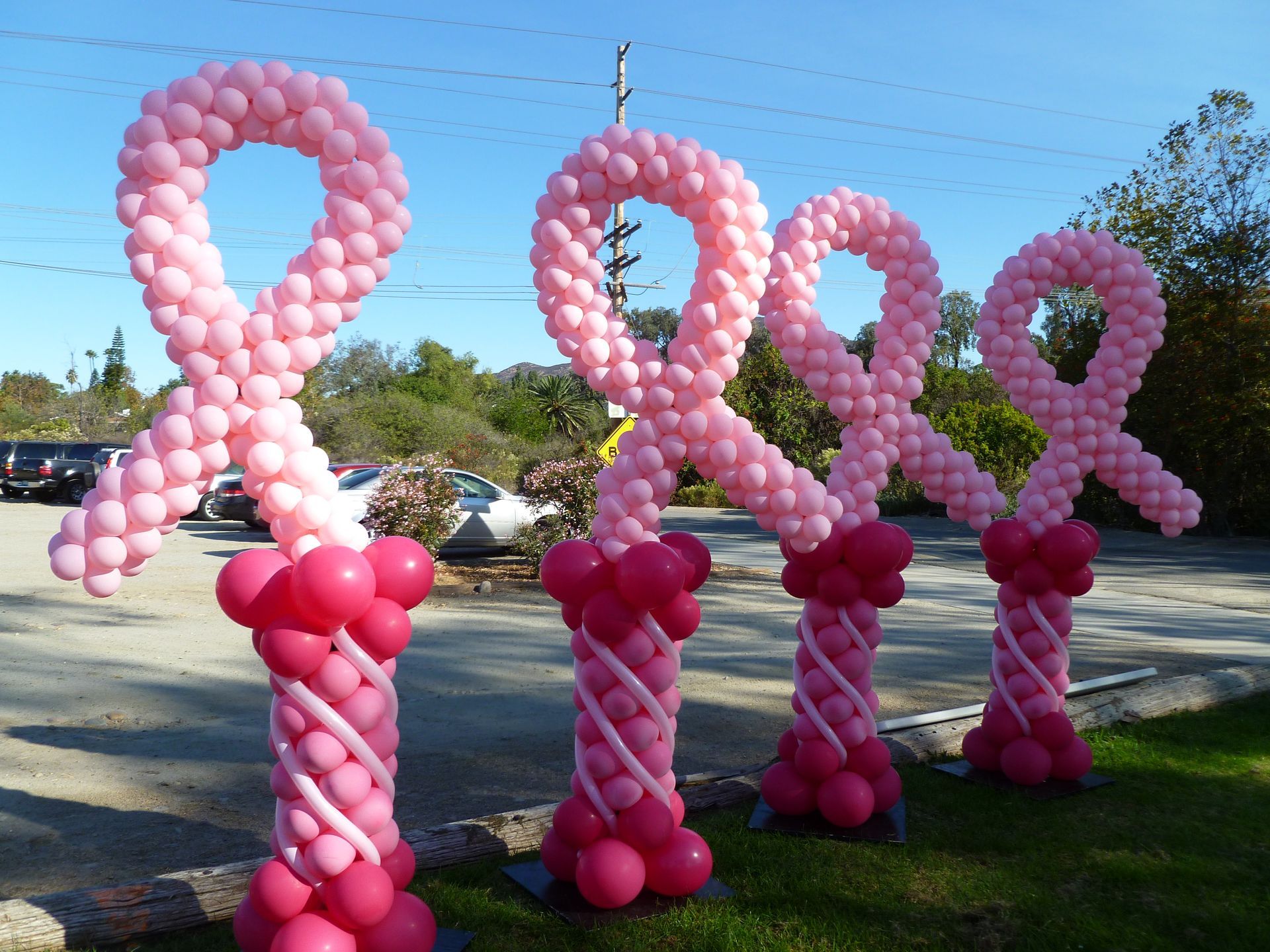 A row of pink balloons in the shape of breast cancer ribbons