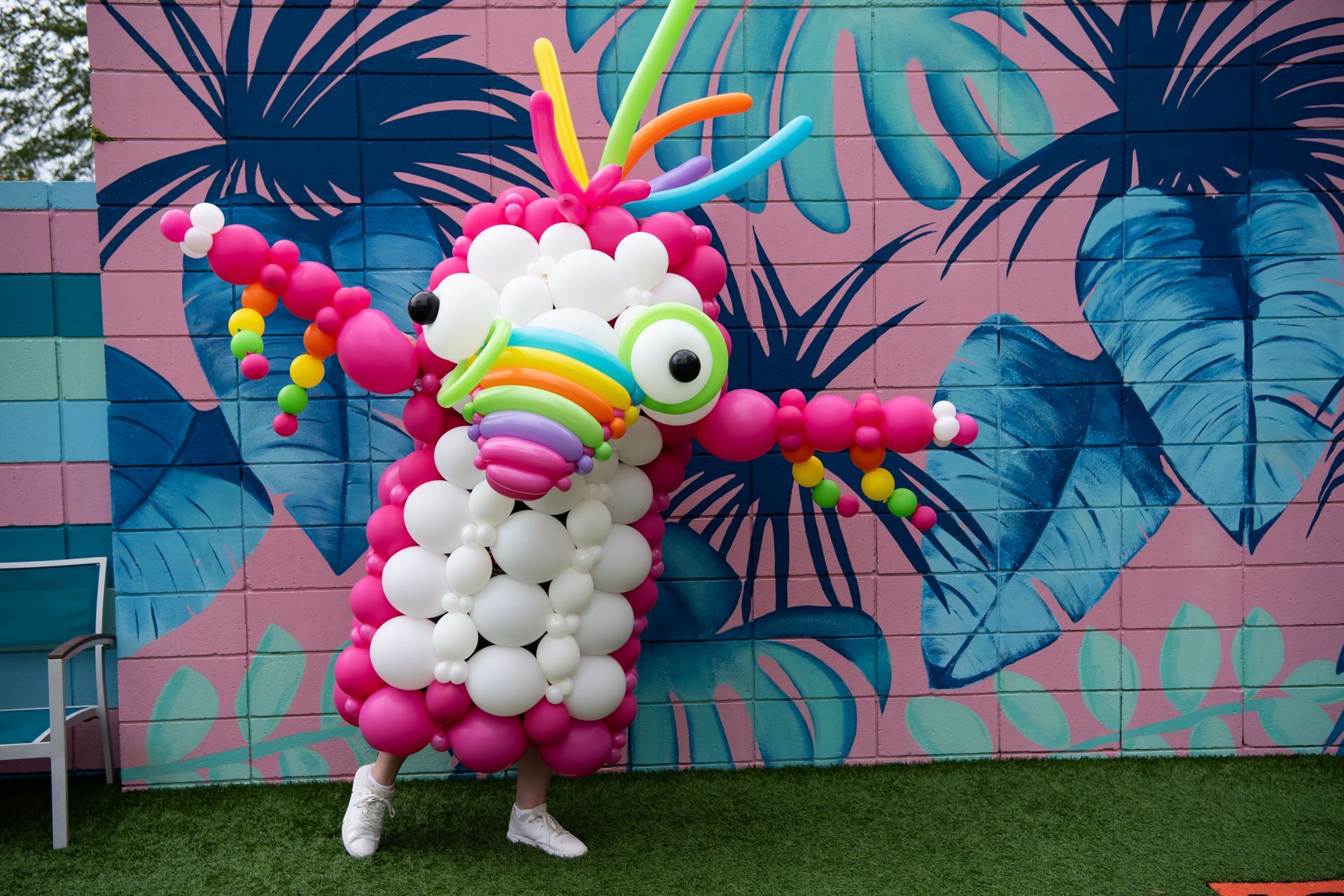 A person is standing in front of a wall made of balloons.